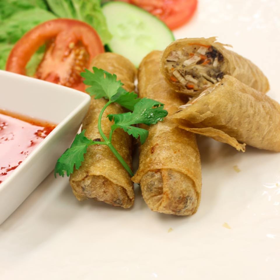 Crispy golden spring rolls with a side of sweet chili sauce and fresh salad.